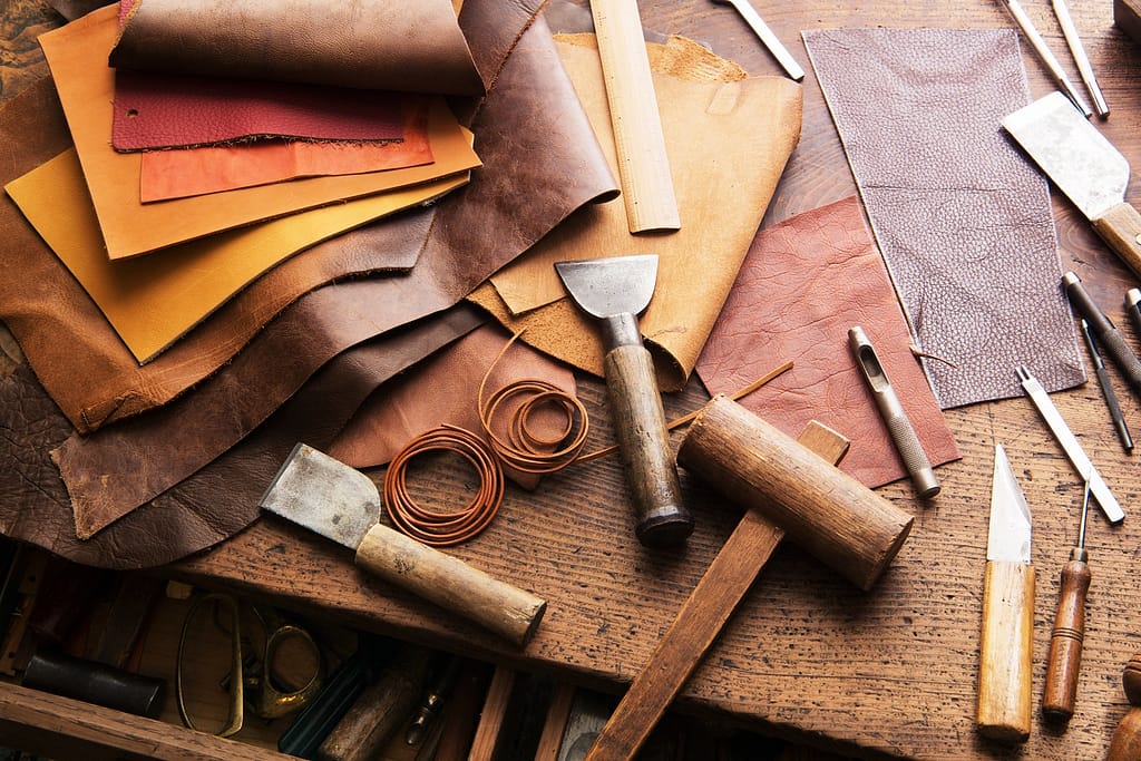 Leather craft or leather working. Selected pieces of beautifully colored or tanned leather on leather craftman's work desk .